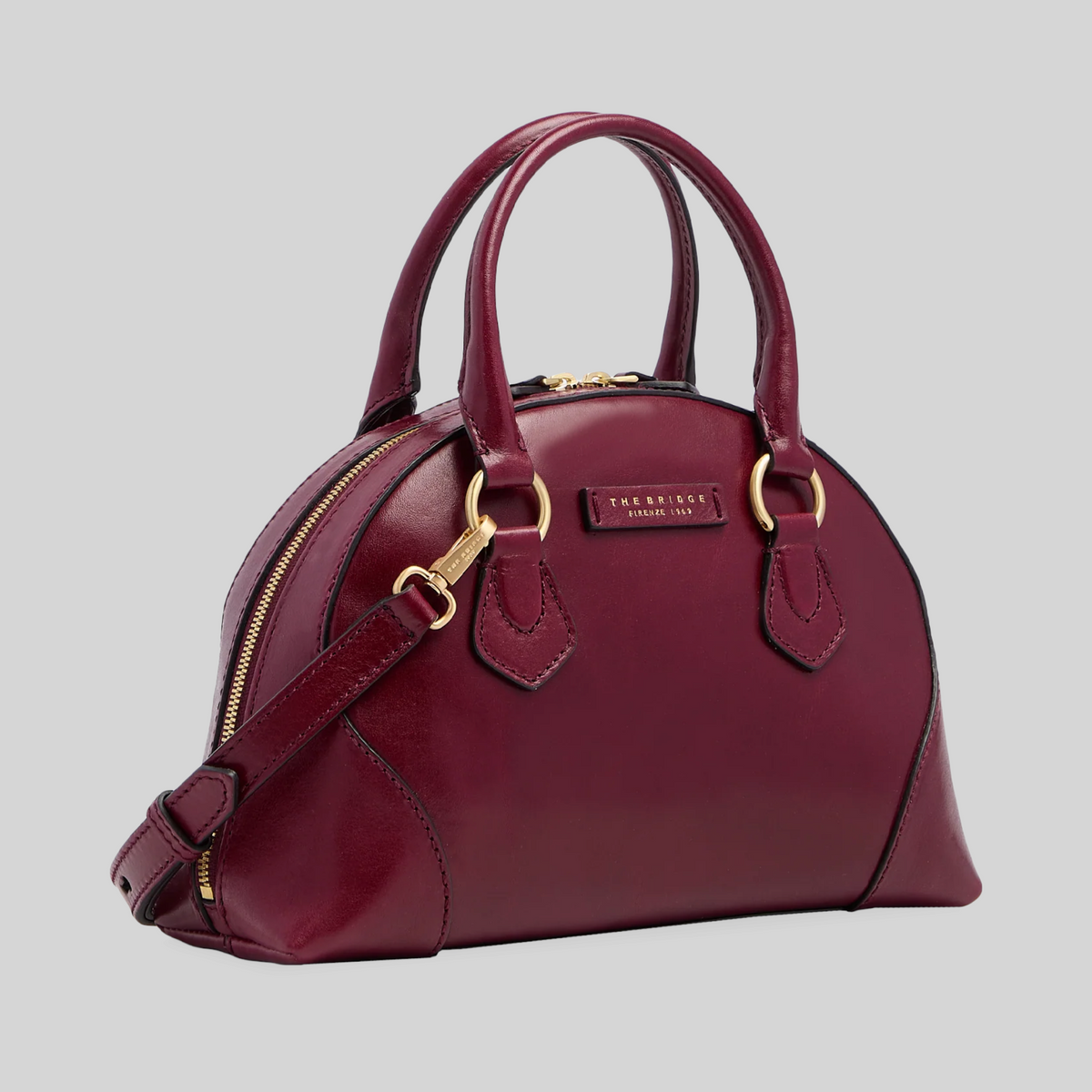 Borsa LIBUTTI in pelle bordeaux con silhouette arrotondata, dettagli dorati e tracolla removibile.