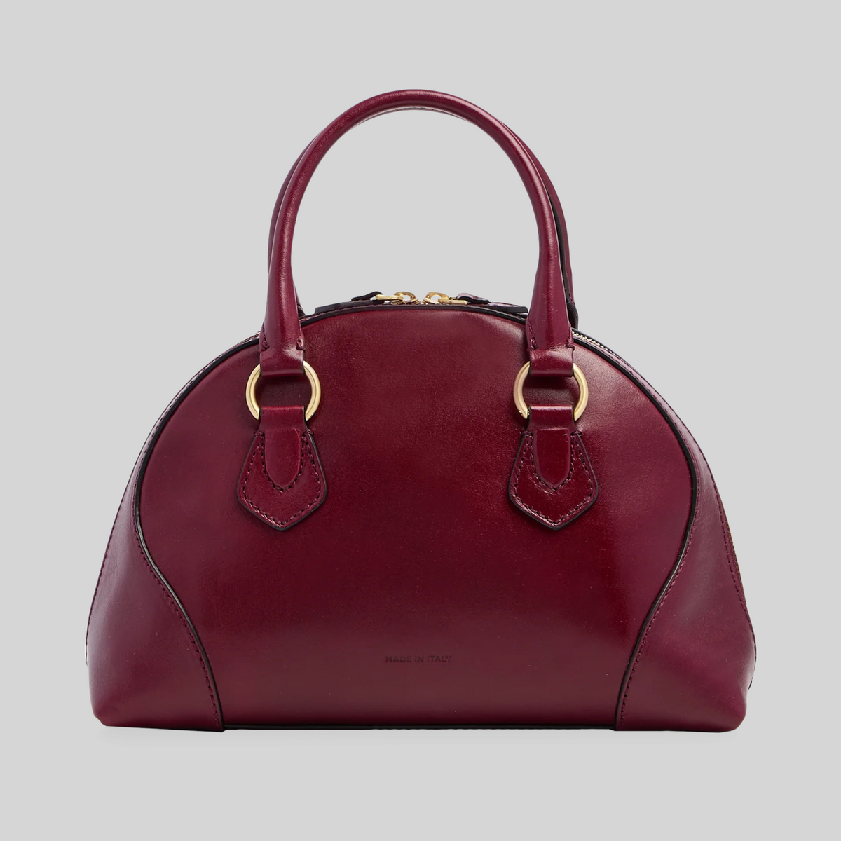 Borsa a mano LIBUTTI in pelle bordeaux con silhouette arrotondata, dettagli dorati e tracolla removibile.