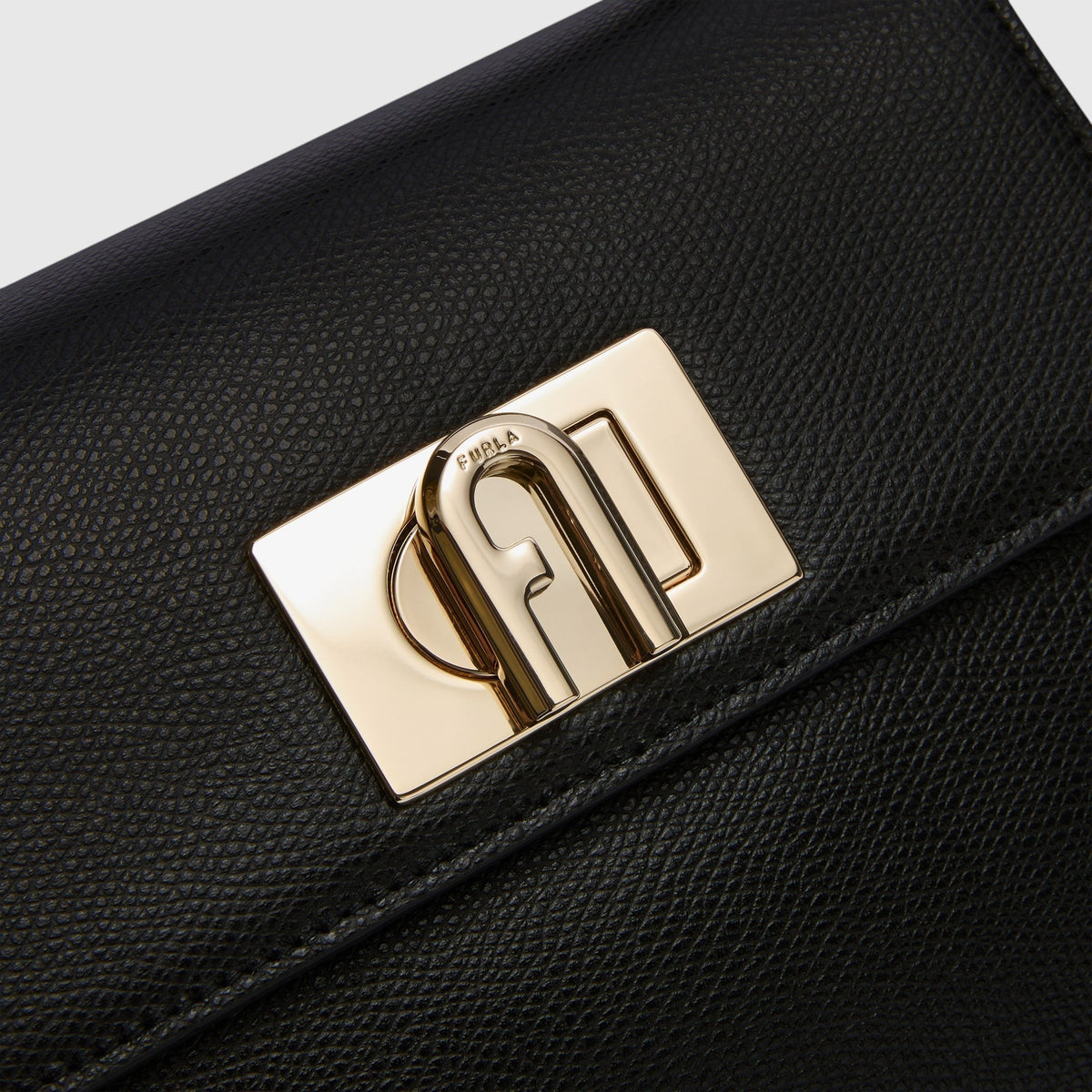 Dettaglio della chiusura a girello dorata con logo Arco su borsa mini nera in pelle granata LIBUTTI