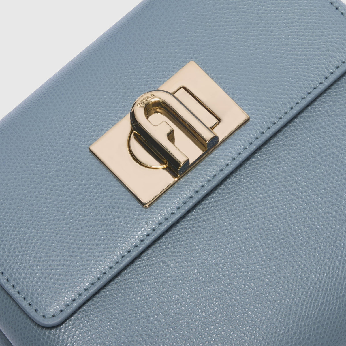 Dettaglio della borsa mini LIBUTTI Furla 1927 in pelle azzurra granata con chiusura a girello dorata e logo Arco.