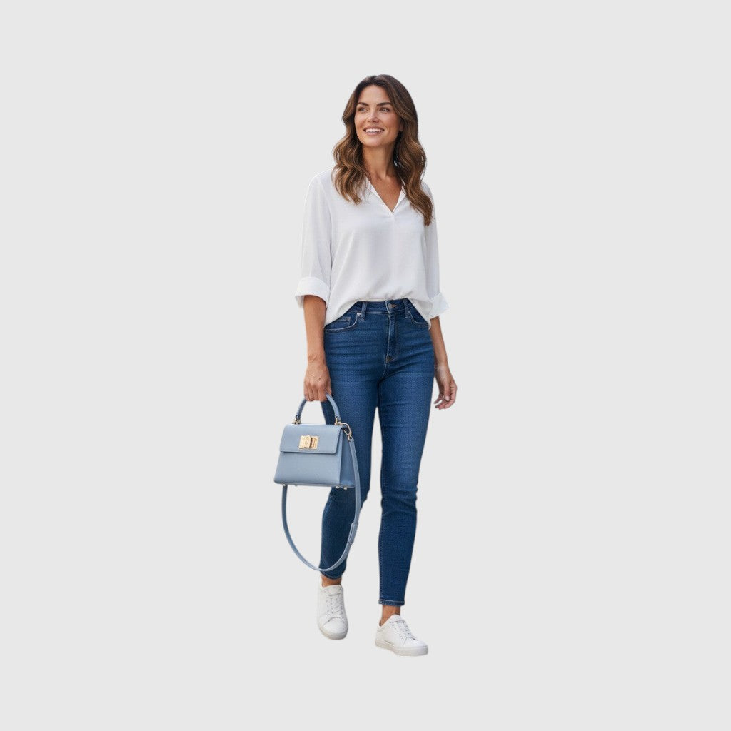 Modella che indossa una mini borsa a mano LIBUTTI Furla 1927 in pelle azzurra con logo Arco e chiusura a girello