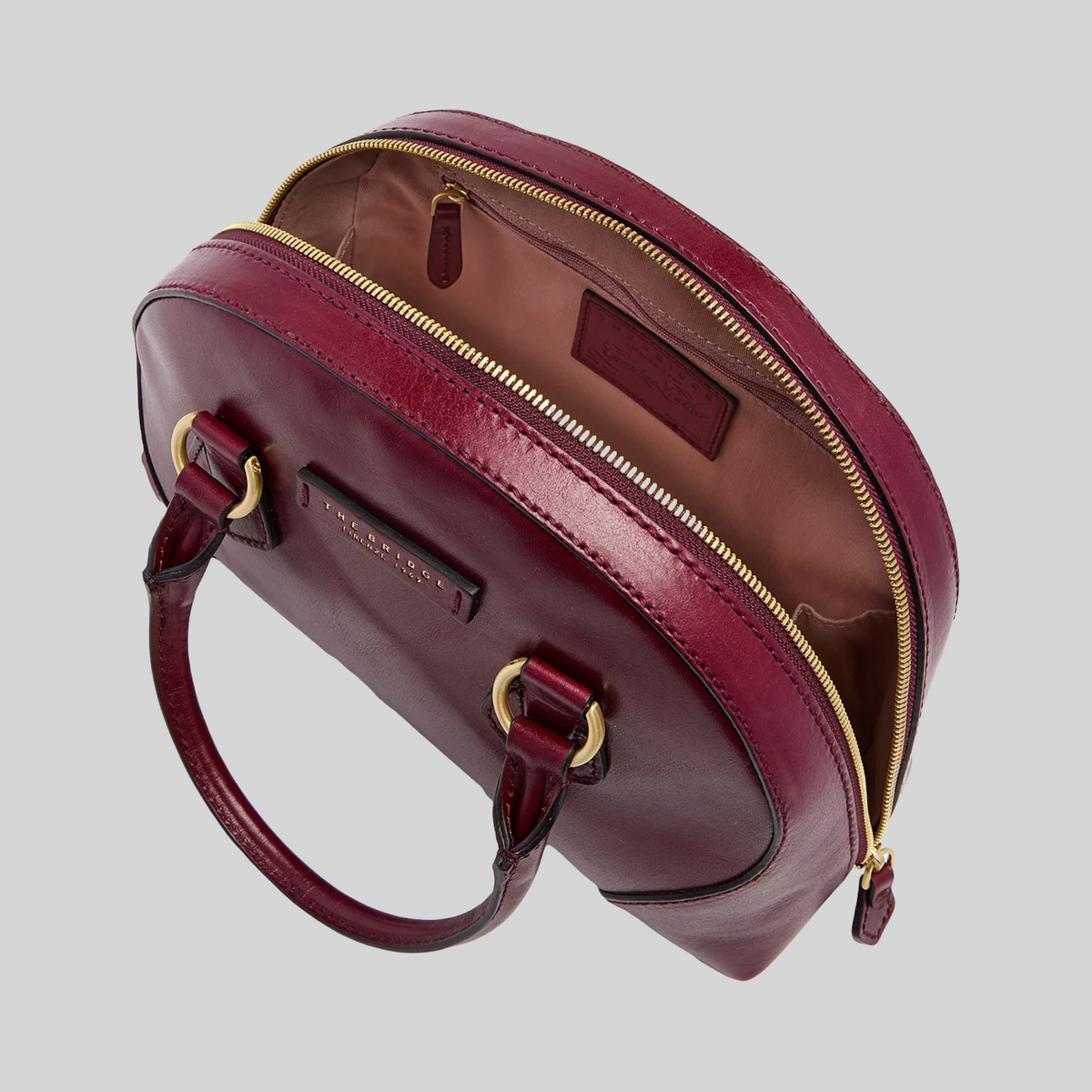 Borsa LIBUTTI in pelle bordeaux con chiusura a zip dorata, design arrotondato e manici eleganti.