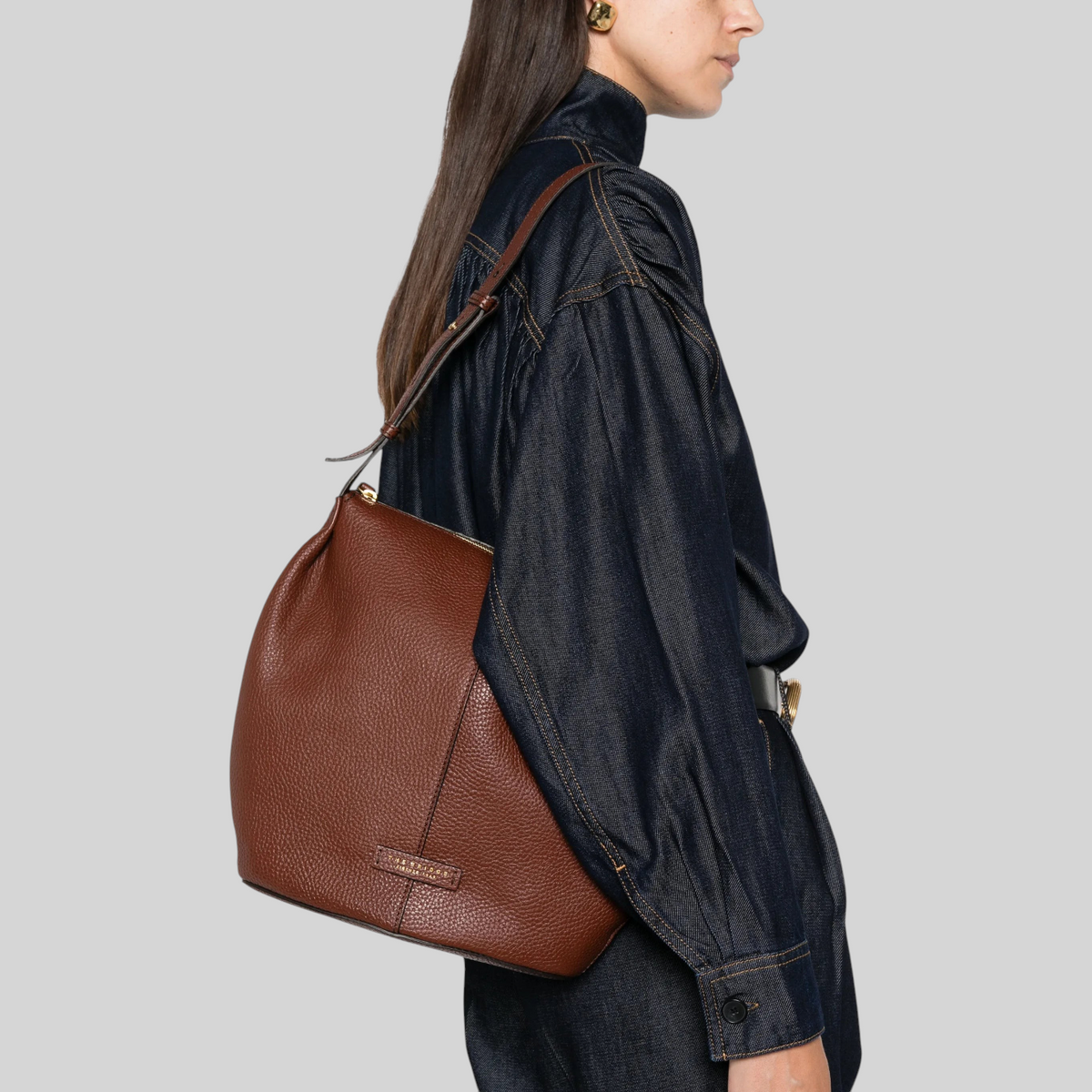 Borsa a spalla LIBUTTI modello HOBO in pelle marrone martellata con finiture dorate indossata lateralmente
