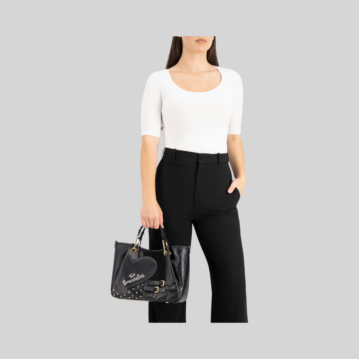 Borsa LIBUTTI Amy piccola in stile patchwork nero con dettagli a cuore, borchie e manici eleganti indossata a mano