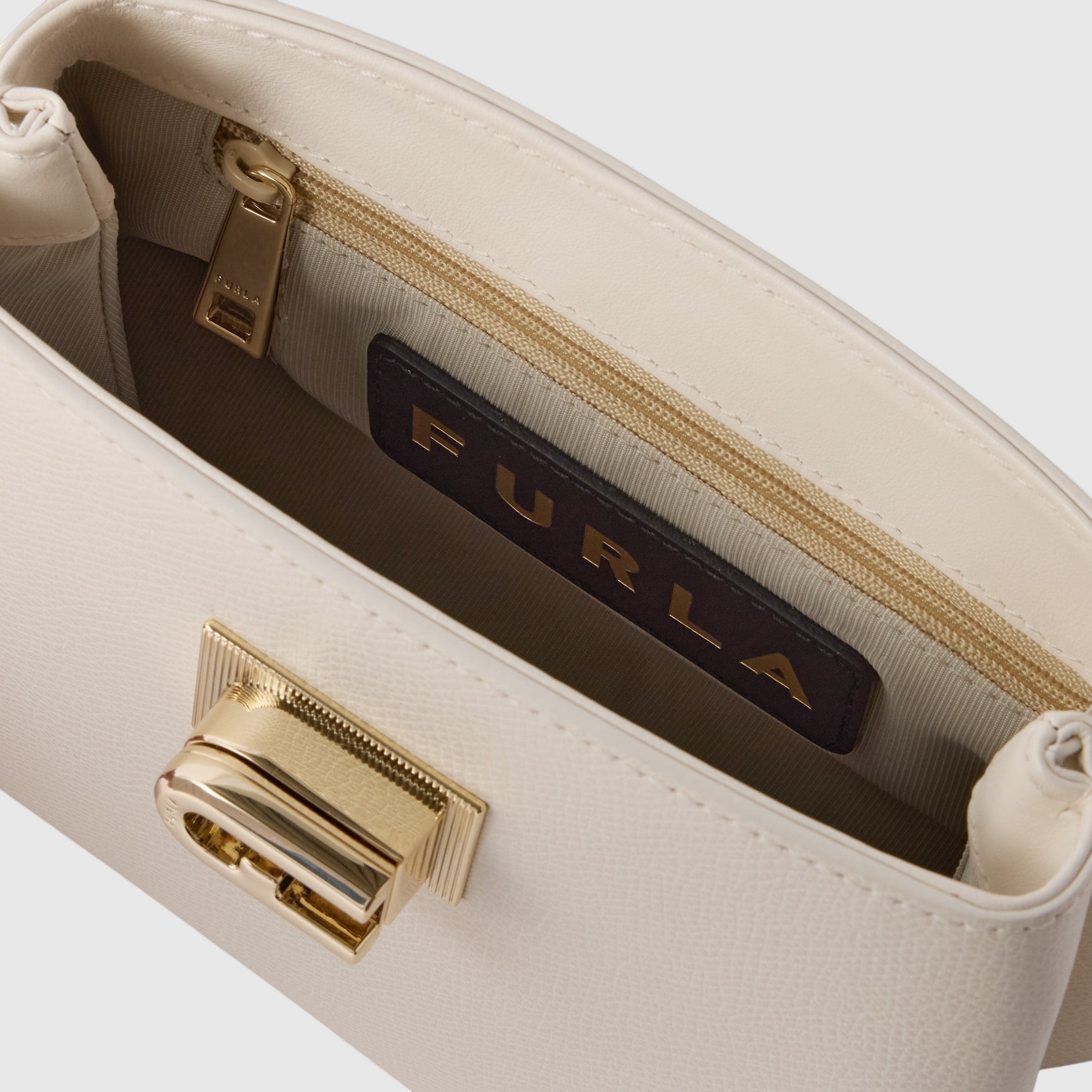 Interno della mini borsa LIBUTTI Furla 1927 in pelle color crema con chiusura a girello dorata e tasca con zip